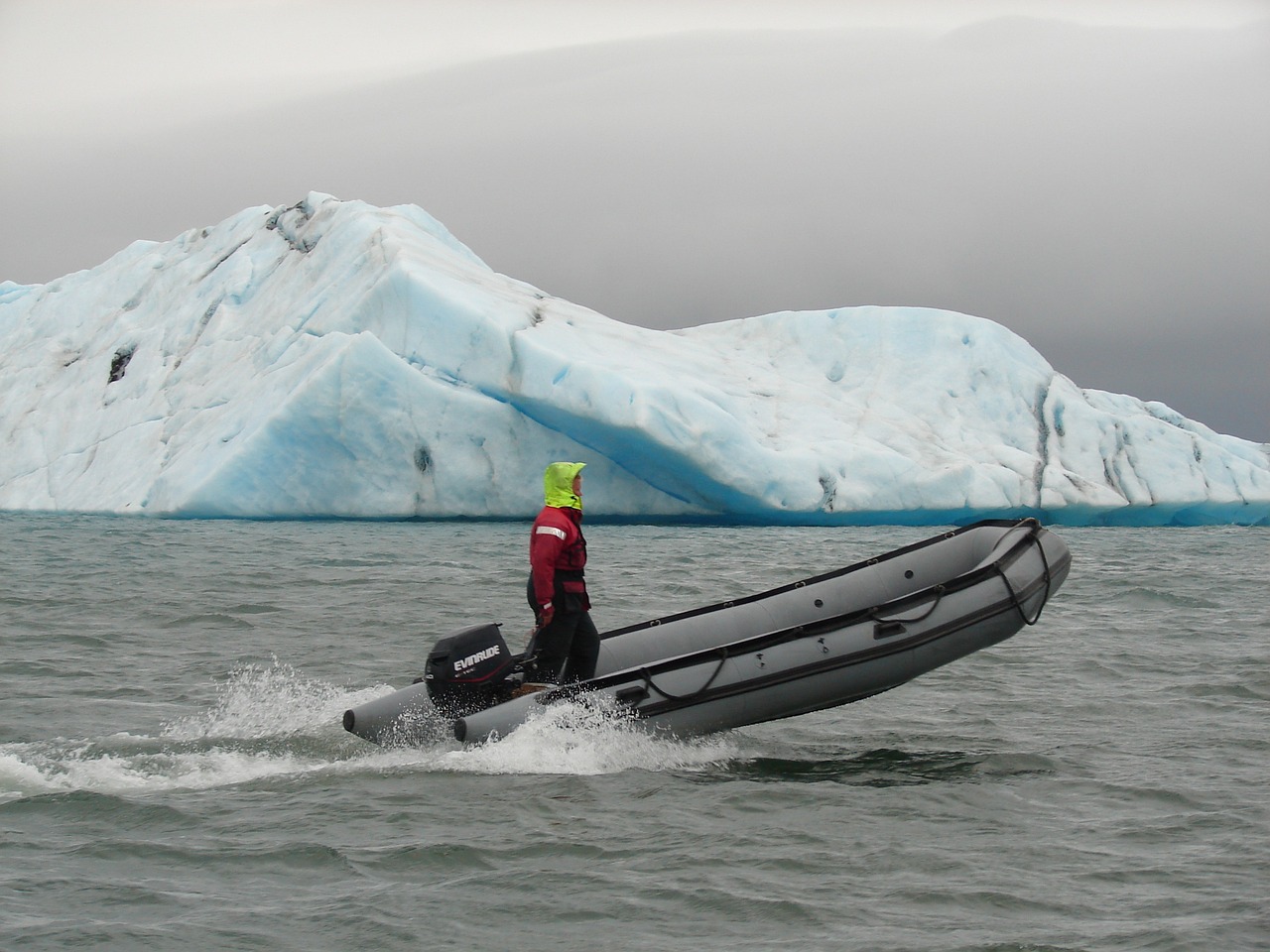 man wearing an inflated life jacket having an adventure out in the ocean near ice on a small boat